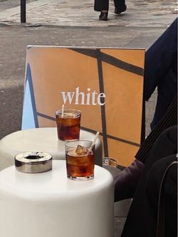 Deux verres de café glacé sur une table ronde blanche devant un panneau avec le mot «white» dans un café à Paris.