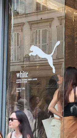 Vitrine du café White Coffee à Paris 10 avec logo Puma et texte sur l'offre de cafés et pâtisseries fraîches.