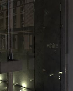 Glass entrance door with the text white, reflecting nearby building structures and street lights