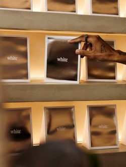 Hand holding a card with the word 'white' among similar cards displayed on shelves at WHITE Coffee - Paris 10.