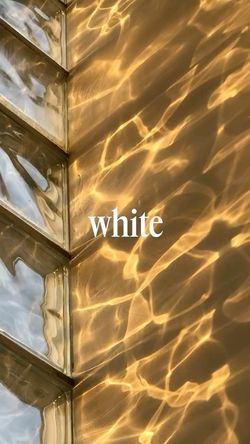 Reflection of light on a textured golden surface with glass blocks on the side and the word "white" in the center.