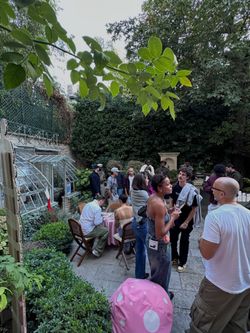 Outdoor cafe terrace at WHITE Coffee - Paris 4 with people socializing among greenery and garden setting.