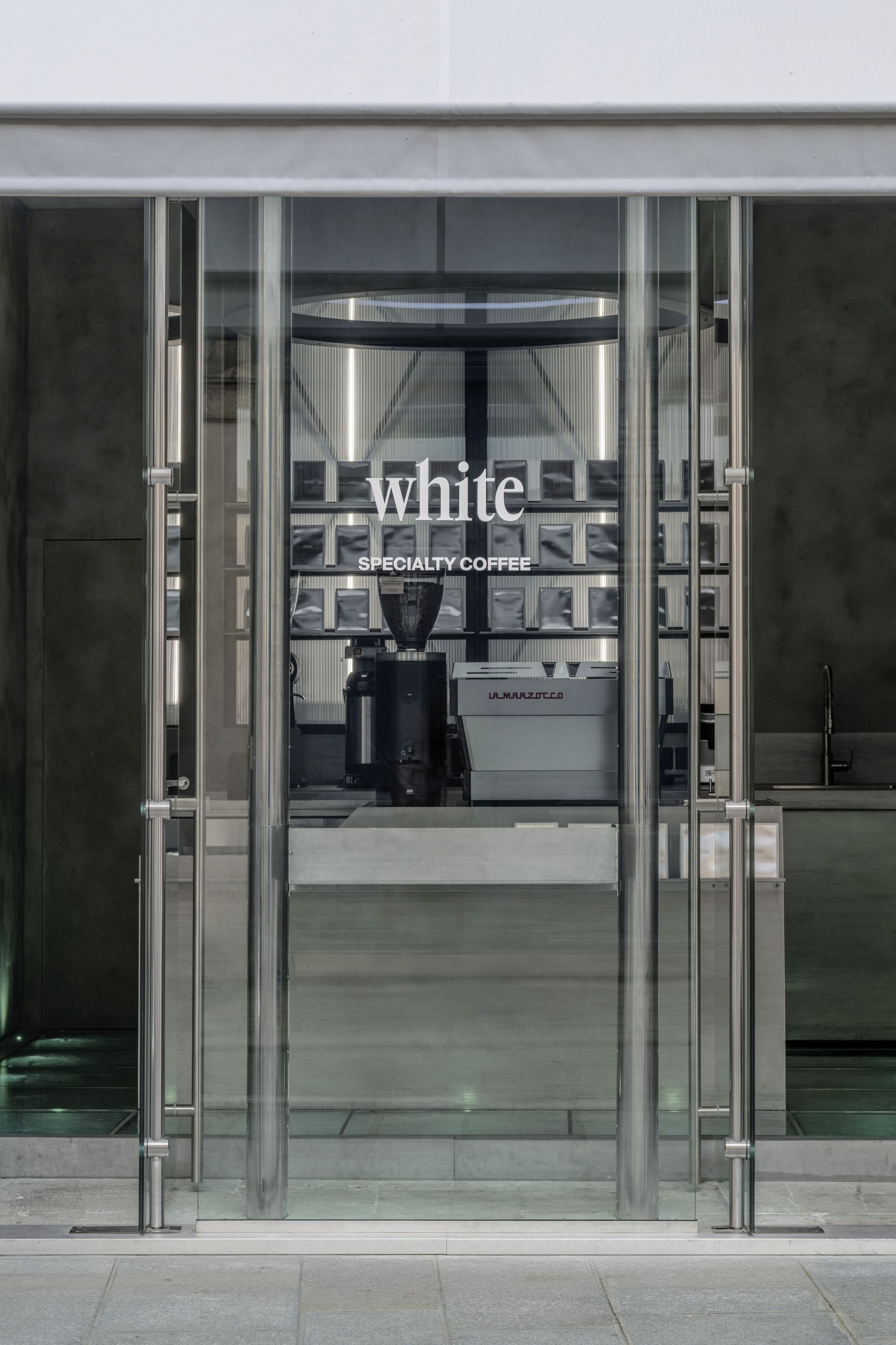 Entrance view of WHITE Coffee featuring a specialty coffee machine and minimalist interior design in Paris.