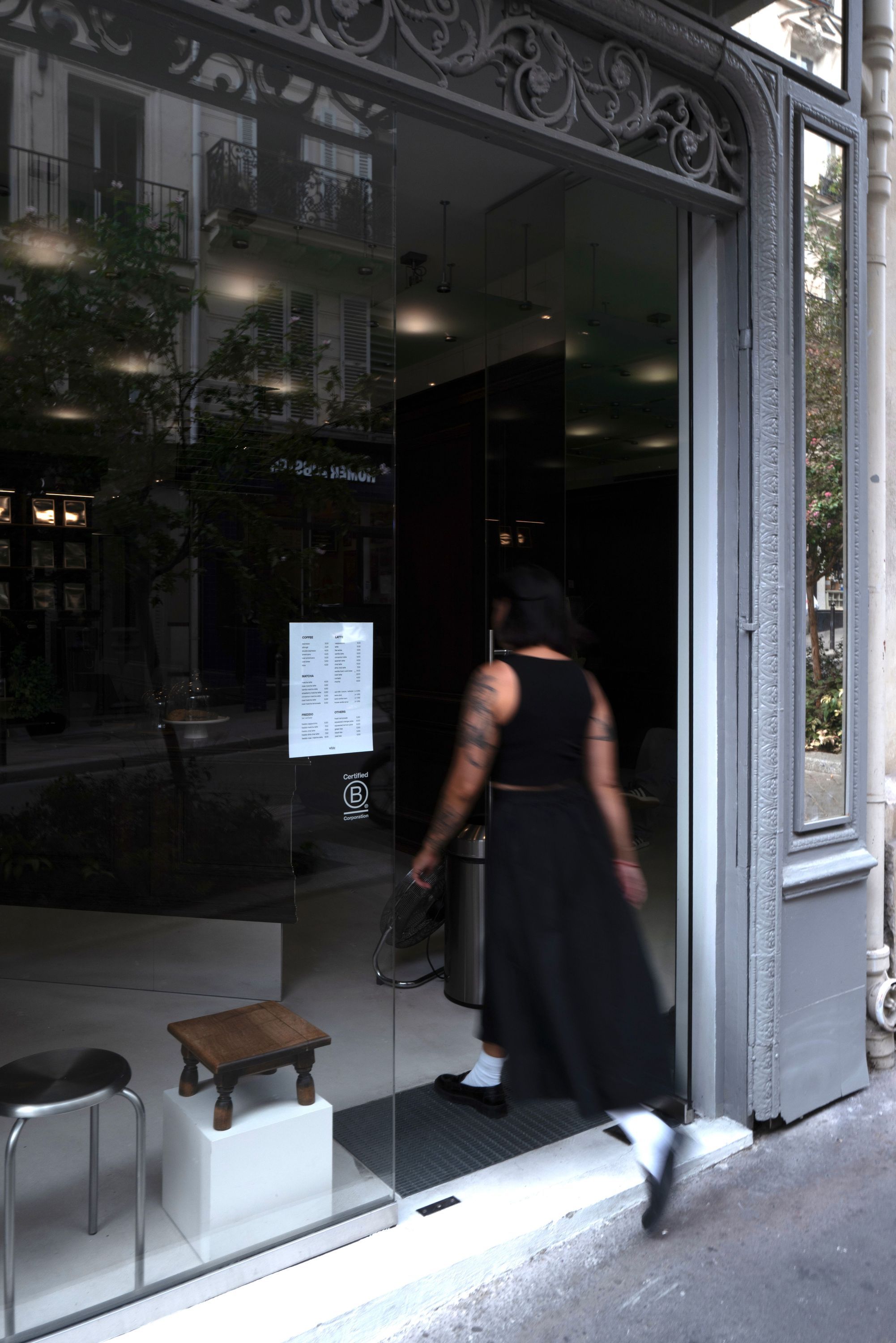 Entrée vitrée du meilleur coffee shop à Paris 9, avec une personne en train d'entrer et une ambiance intérieure moderne.