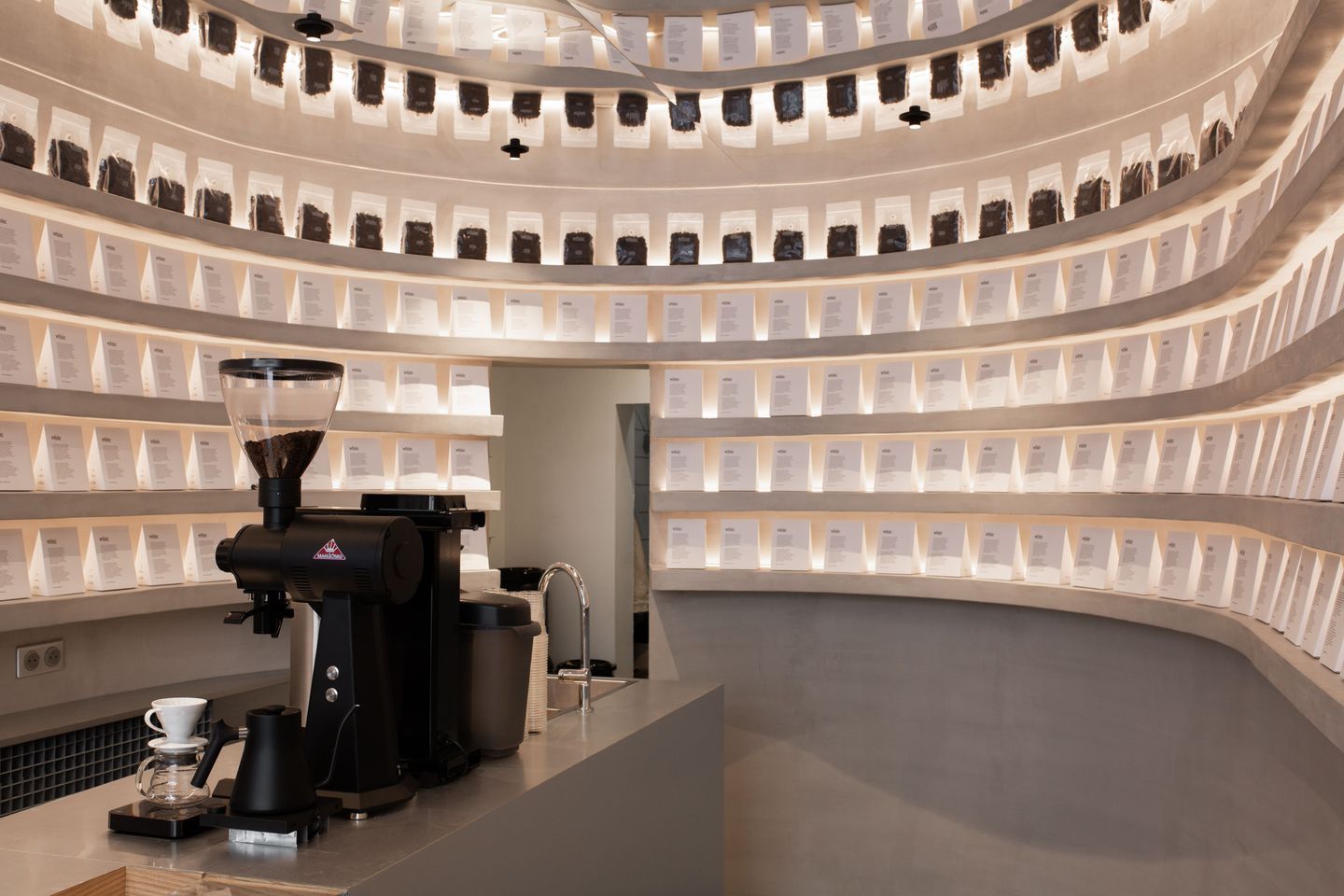 A sleek coffee bar featuring a professional grinder and neatly arranged coffee bags on display.