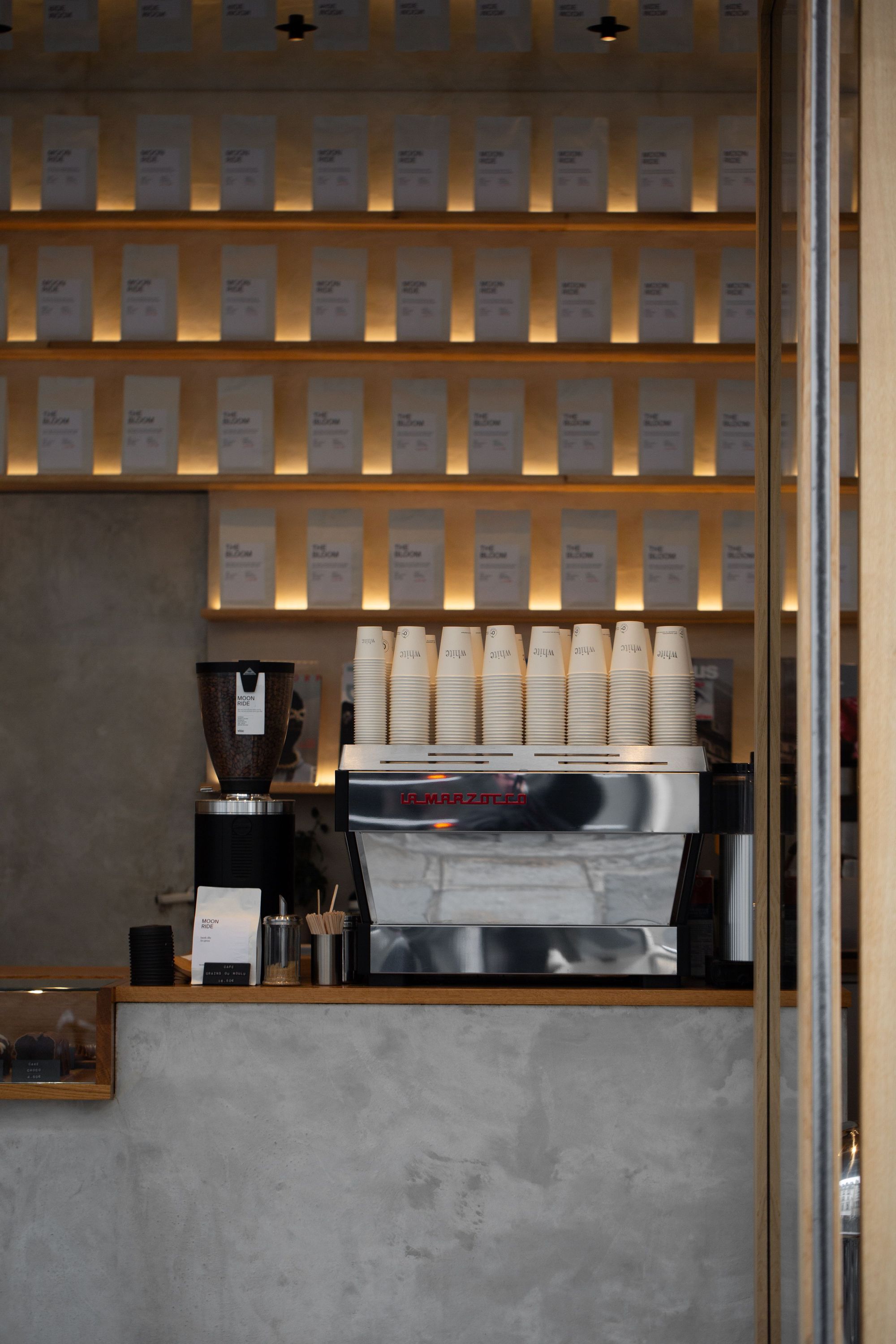 Café moderne avec machine à café ajourée et étagères lumineuses, distingué comme meilleur coffee shop à Paris.