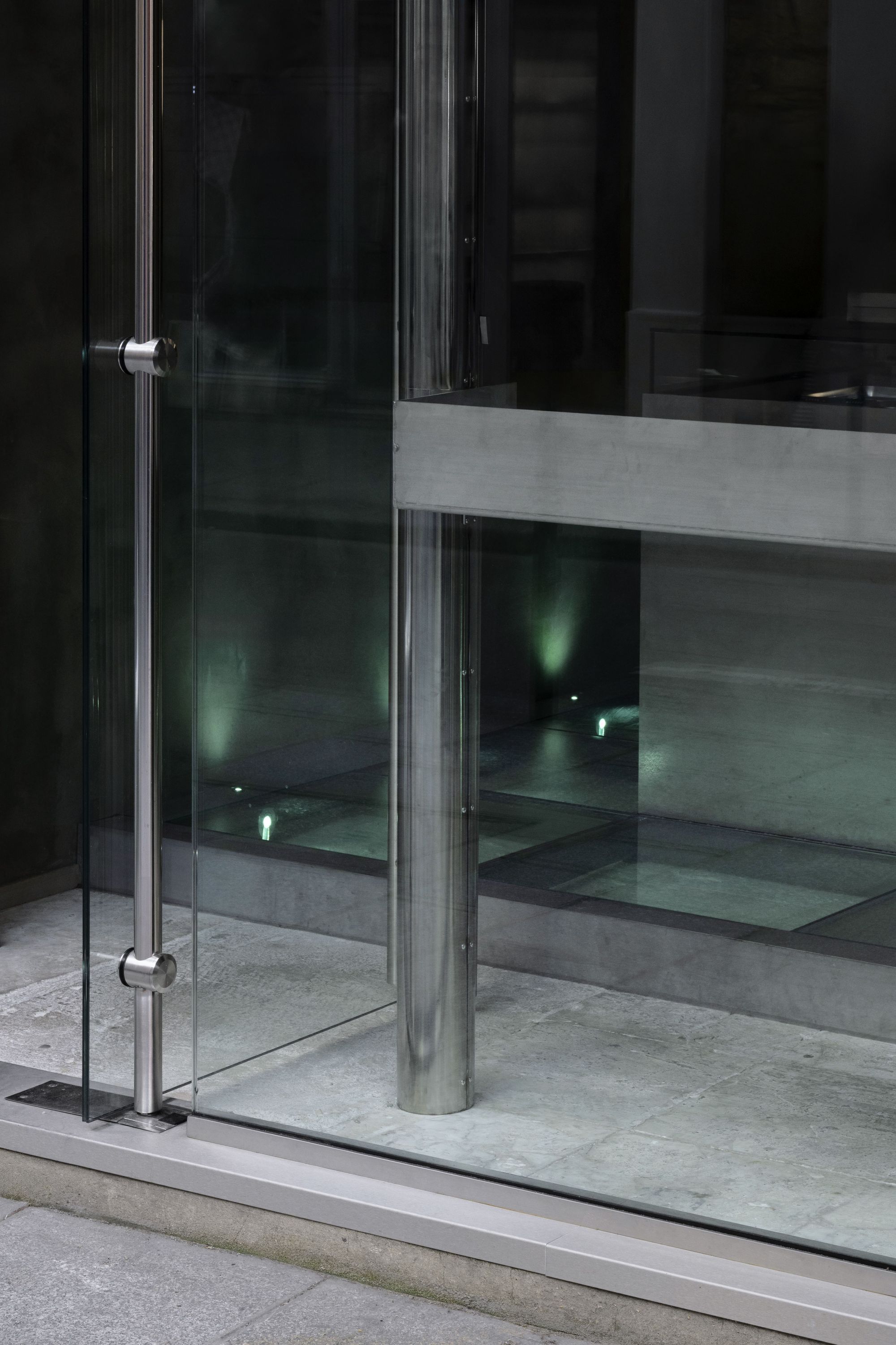Glass door entrance with metal handles and concrete floor at WHITE Coffee - Paris 4