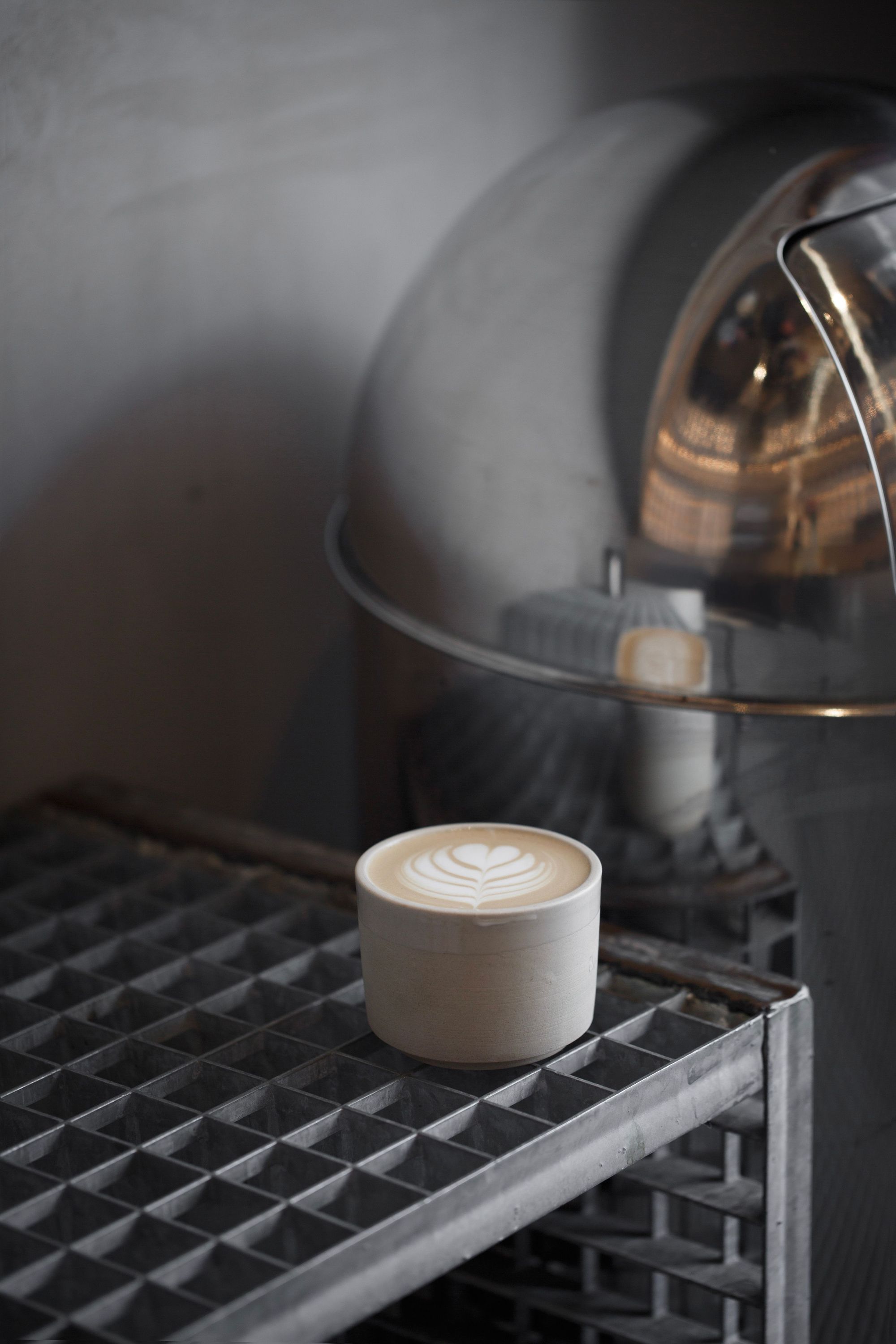 Un café avec un joli motif de latte art, posé sur un support en métal.