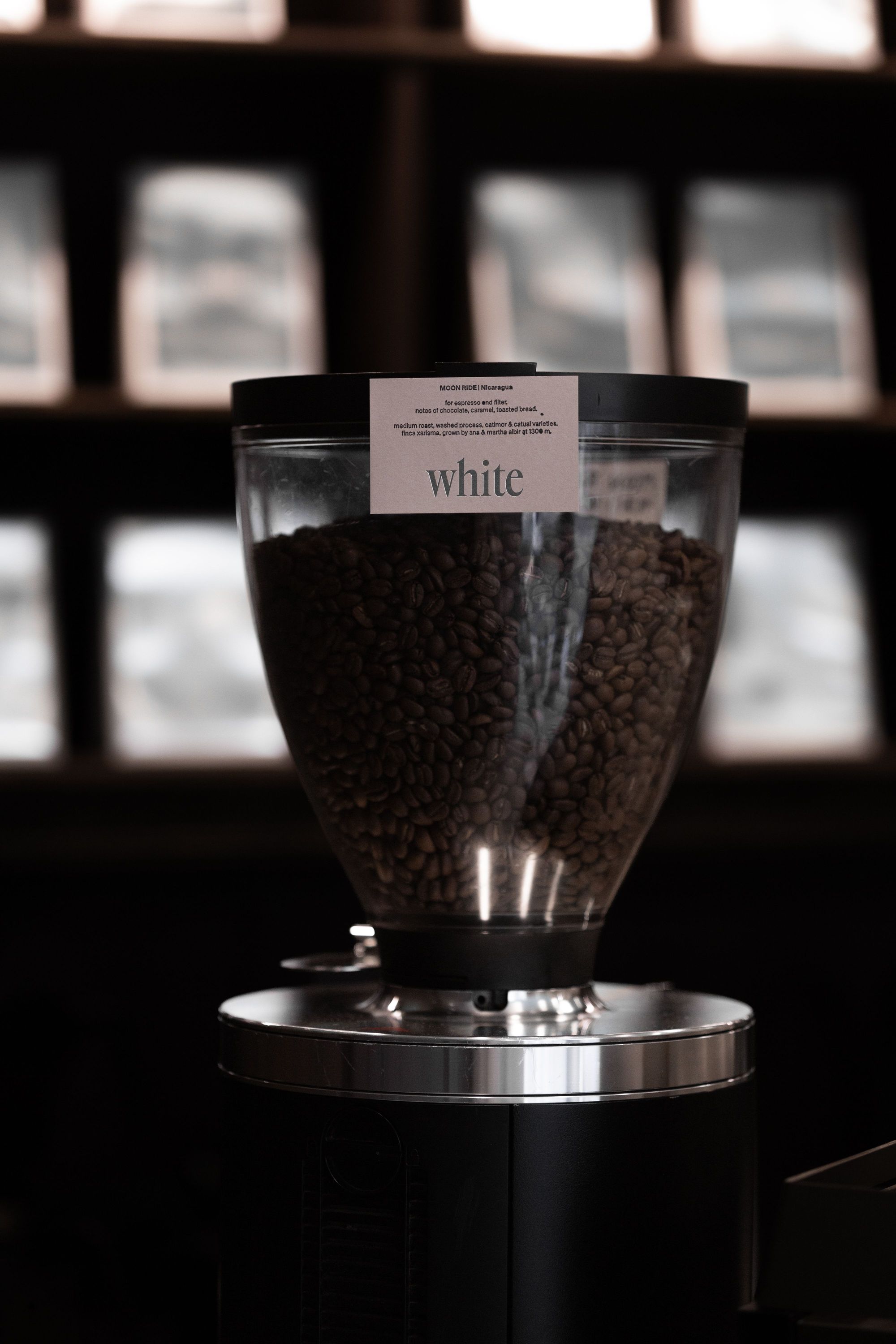 Récipient transparent rempli de grains de café avec une étiquette "white" dans un coffee shop à Paris 9.