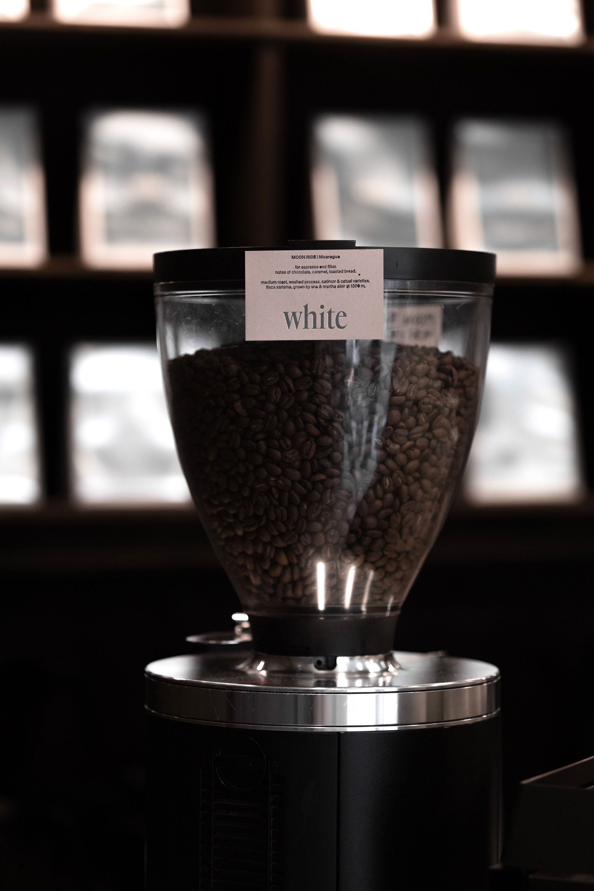 Coffee bean grinder filled with roasted beans inside WHITE Coffee shop in Paris 9, showcasing its specialty coffee focus.