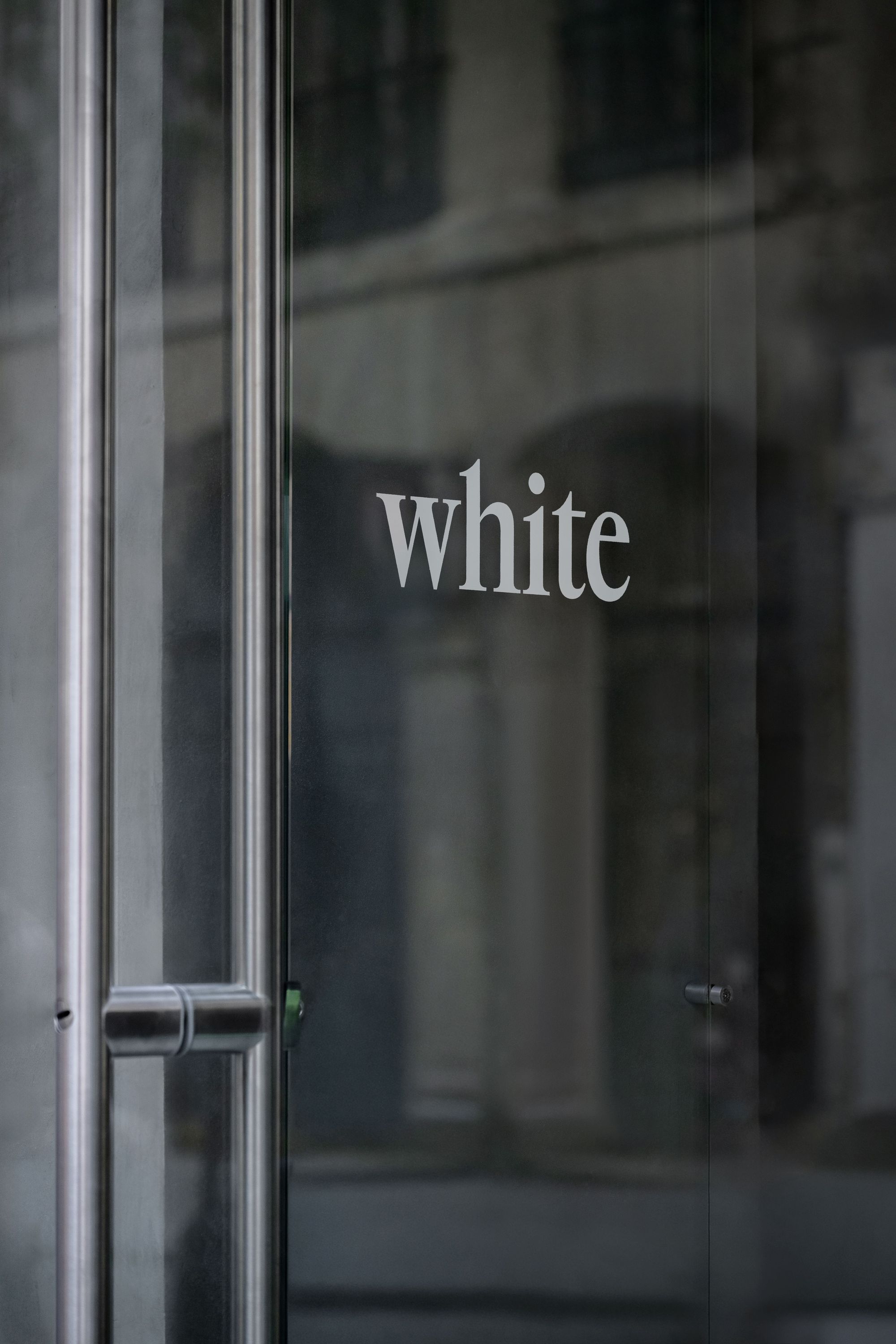 Glass door with the word 'white' in white lettering at WHITE Coffee - Paris 4 café.