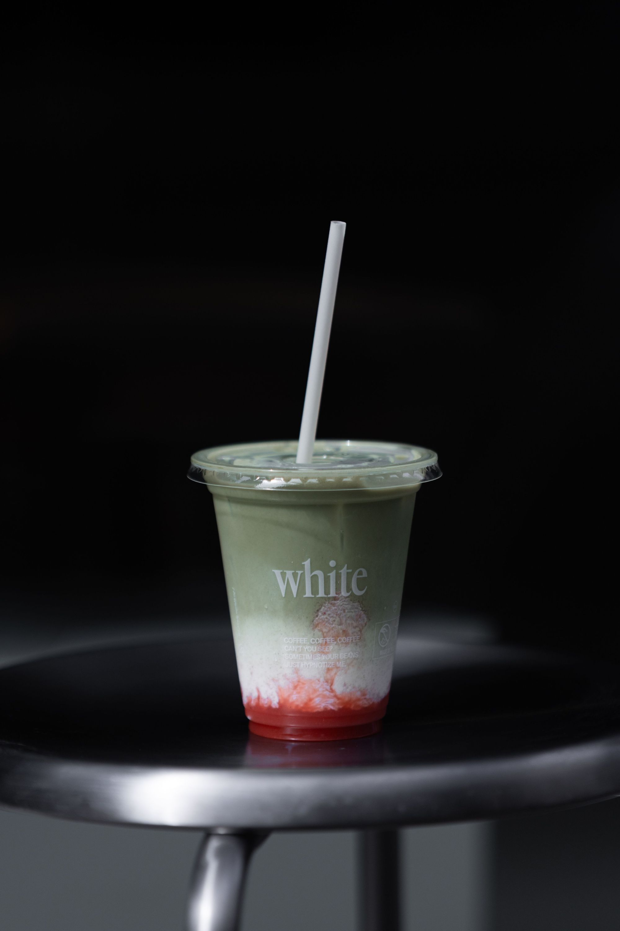 Cold matcha drink with layers of green tea and red syrup served in a plastic cup with a straw at WHITE Coffee - Paris 9.
