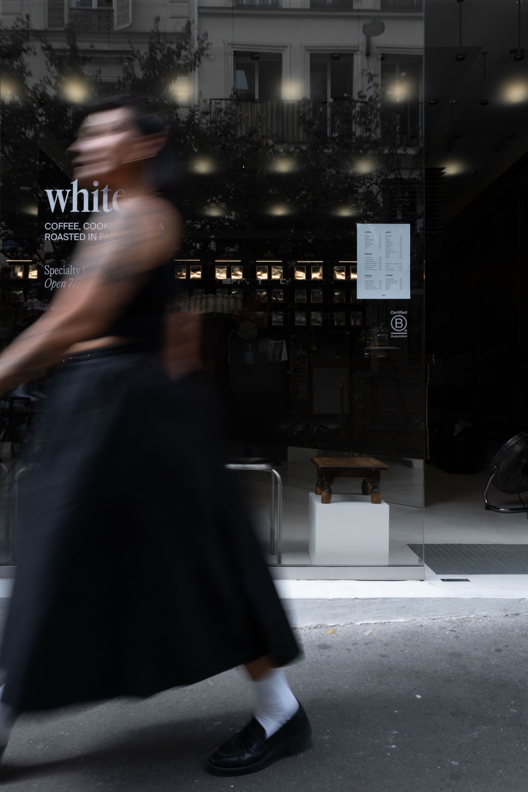 Exterior view of WHITE Coffee shop in Paris 9 with a blurred person walking past the entrance door